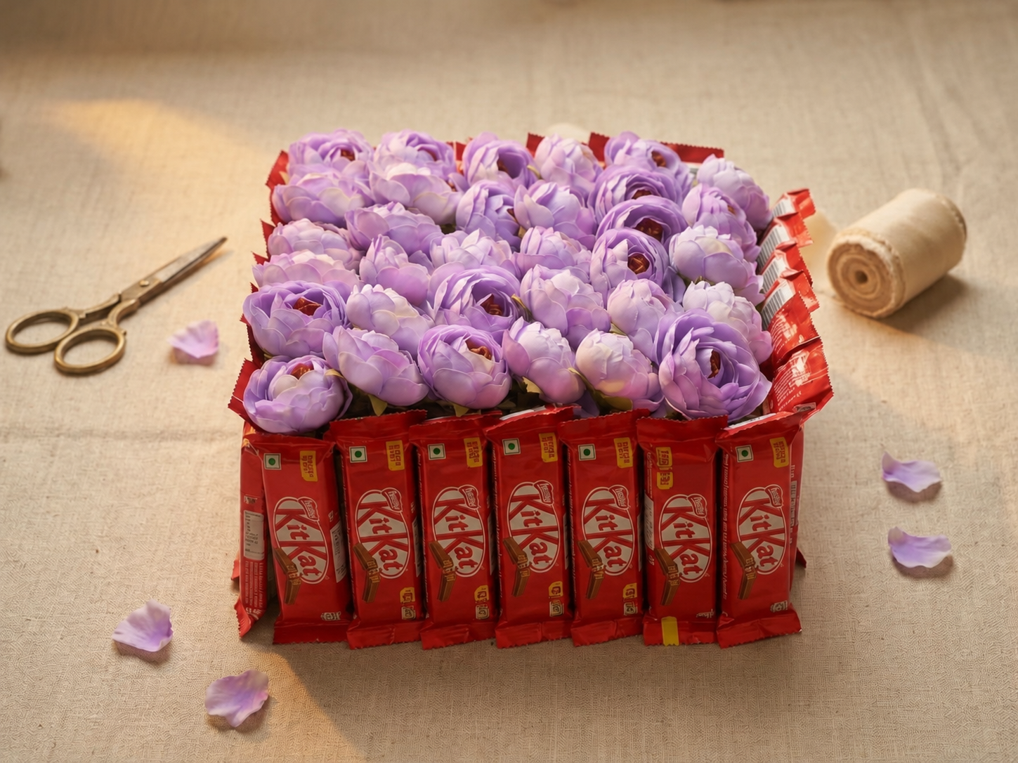 Lilac flower arrangement surrounded by KitKat chocolates, angled view